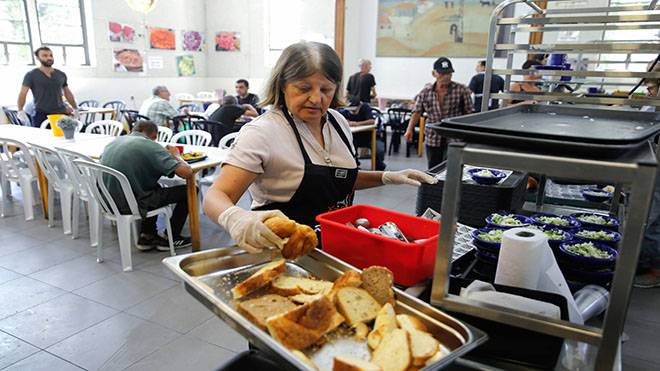 موظف مطبخ حساء في مطعم Lasova يقدم الخبز للمحتاجين في مدينة تل أبيب